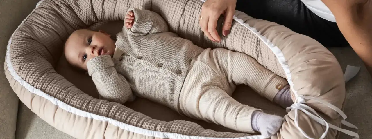 Ein hochsensibles Baby liegt in einer kuscheligen Nestchen. Die sanften Farben und die weichen Stoffe schaffen Geborgenheit f&uuml;r das kleine Wesen.